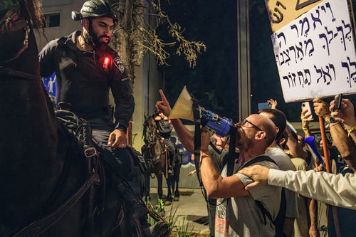 A protestor against Israeli Prime Minister Benjamin Netanyahu points at a mounted police officer during a demonstration in Tel Aviv on July 20, 2024. Over 100,000 Israelis demonstrated in Kaplan with the hostage's families, demanding an immediate hostage deal and ceasefire.