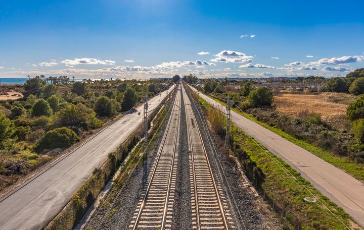 Two straight and infinite railroad tracks seen from above on a sunny day.