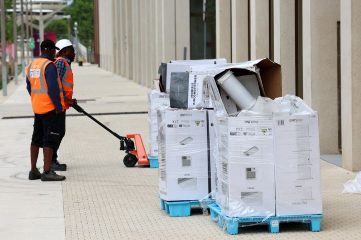 Εργαζόμενοι φορτώνουν κλιματιστικά στο χώρο του Ολυμπιακού χωριού όπου οι αθλητές θα στεγαστούν στο Saint-Denis, ένα κοντινό προάστιο του Παρισιού, στις 2 Ιουλίου 2024. (Photo by Emmanuel Dunand / AFP) (Photo by EMMANUEL DUNAND/AFP via Getty Images)