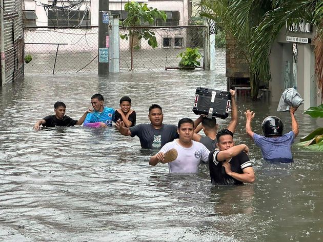 Άνθρωποι περπατούν μέσα από έναν πλημμυρισμένο δρόμο μετά από βροχές μουσώνων που επιδεινώθηκαν από τον υπεράκτιο τυφώνα Gaemi την Τετάρτη, 24 Ιουλίου 2024, στη Μανίλα των Φιλιππίνων.