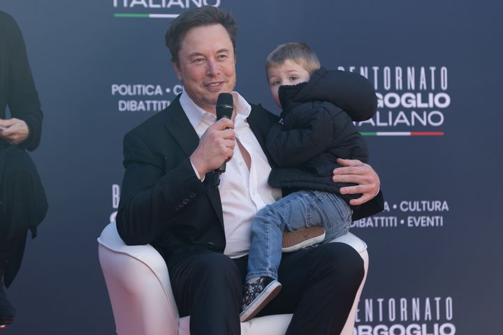 Musk speaks to an audience in Rome while holding one of his younger children in 2023. Musk has 12 children.