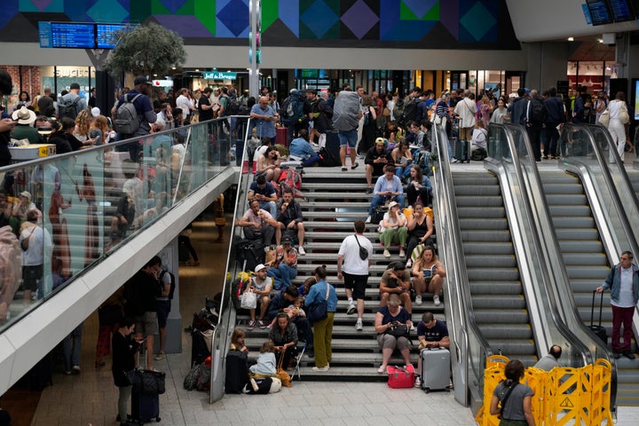 Travelers sit on stairs at the Gare de Montparnasse, at the 2024 Summer Olympics, Friday, July 26, 2024, in Paris, France. Hours away from the grand opening ceremony of the Olympics, high-speed rail traffic to the French capital was severely disrupted on Friday following what officials described as 