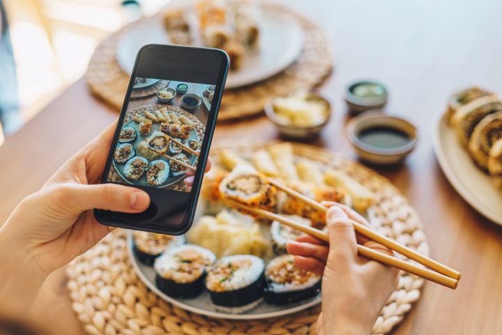 Woman taking photo of a sushi plate with smartphone