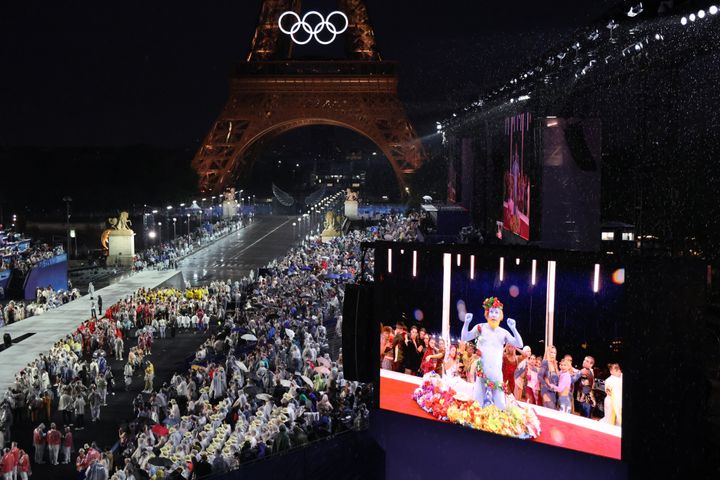 PARIS, FRANCE - JULY 26: Delegations arrive at the Trocadero as spectators watch French singer Philippe Katerine performing on a giant screen during the Opening Ceremony of the Olympic Games Paris 2024 on July 26, 2024 in Paris, France. (Photo by Ludovic Marin - Pool/Getty Images)