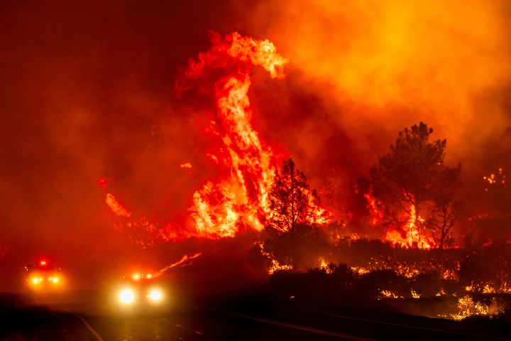 Flammen schlagen über Feuerwehrautos, als der Parkbrand am Freitag, 26. Juli 2024, die Interstate 36 in der Nähe von Pines Creek im Tehama County, Kalifornien, überquert.