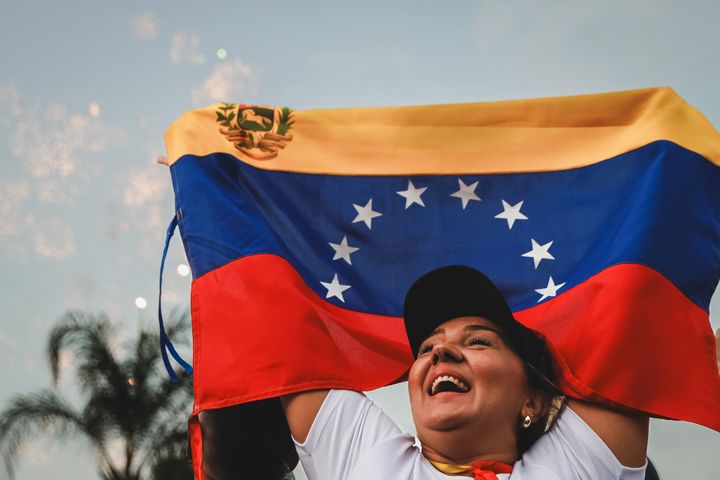 A Venezuelan migrant waves a Venezuelan flag as they gather to await official results for the presidential election in Venezuela on July 28, 2024 in Guayaquil, Ecuador. (Photo by Agencia Press South/Getty Images)