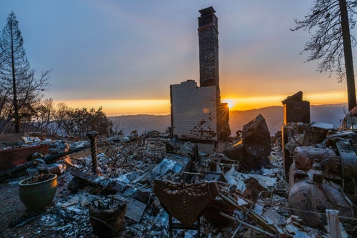 The sun sets over the remains of a house that was destroyed in the Park Fire near Forest Ranch, on Saturday.