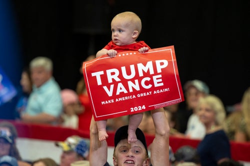 A man lifts a baby holding a "Trump Vance" sign at a rally for Republican vice presidential nominee JD Vance inside Radford University's Dedmon Center in Radford, Virginia, on July 22, 2024.