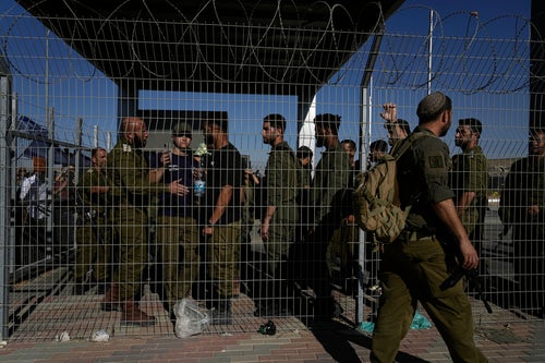 Israeli soldiers gather at the gate to the Sde Teiman military base, where inside, soldiers are being questioned for detainee abuse, Monday, July 29, 2024. The Israeli military said Monday it was holding nine soldiers for questioning following allegations of "substantial abuse" of a detainee at a shadowy facility where Israel has held Palestinian prisoners throughout the war in Gaza. (AP Photo/Tsafrir Abayov)