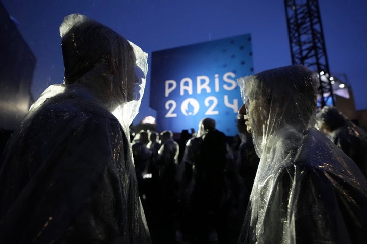 Musicians wait in the rain before performing, in Paris, France, during the opening ceremony of the 2024 Summer Olympics, Friday, July 26, 2024. (AP Photo/Robert F. Bukaty)