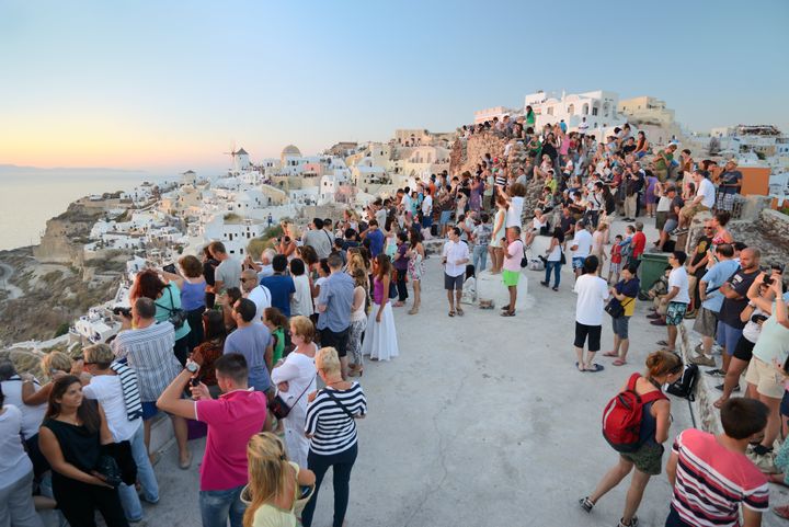 Oia, Santorini, Greece - September 3, 2013: Tourist Crowd watching the sunset in front of the famous old town Oia on Santorini.