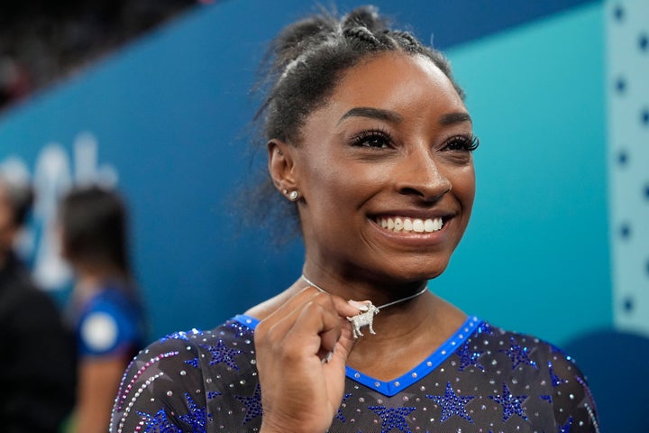 Simone Biles celebrates with her GOAT necklace after winning the gold medal during the women's artistic gymnastics all-around finals Thursday.