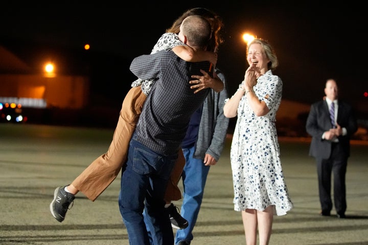 Reporter Evan Gershkovich hugs his mother Ella Milman, left, at Andrews Air Force Base, Md., following his release. Looking on at right is Elizabeth Whelan, sister of released prisoner Paul Whelan.