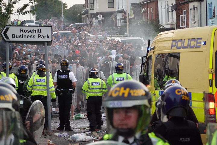 Riot police hold back protesters after disorder broke out on July 30, 2024 