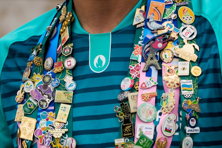 Olympic pins are worn by a volunteer in Paris, France, prior to the start of the opening ceremony of the 2024 Summer Olympics, Friday, July 26, 2024. (AP Photo/Andy Wong)