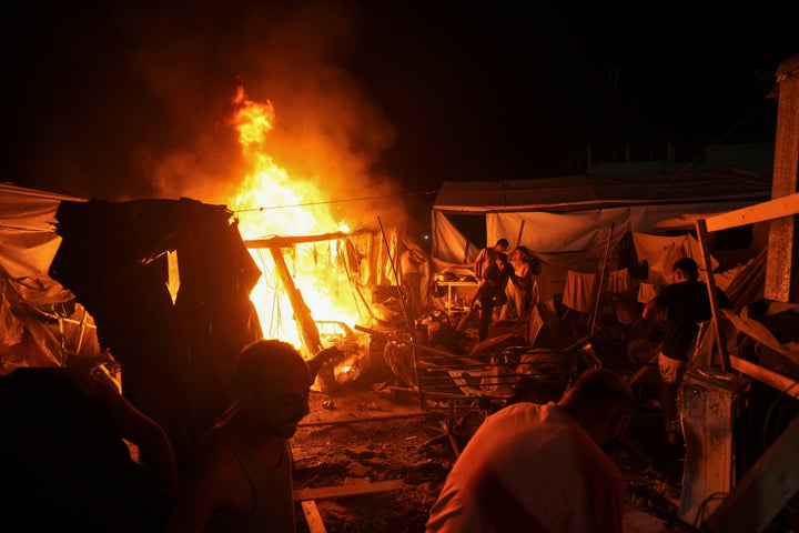 Palestinians react to fire from an Israeli strike that hit a tent area in the courtyard of Al Aqsa Martyrs hospital in Deir al Balah, Gaza Strip, Sunday, Aug. 4, 2024. The strike killed several people including a woman and injured others, health officials confirmed. (AP Photo/Abdel Kareem Hana)