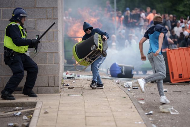 Riot police officers push back anti-migration protesters outside the Holiday Inn Express Hotel which is housing asylum seekers on August 4, 2024.