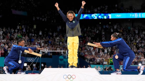 Simone Biles and Jordan Chiles of the United States bow to gold medalist Rebeca Andrade of Brazil in the medal ceremony for the floor final.