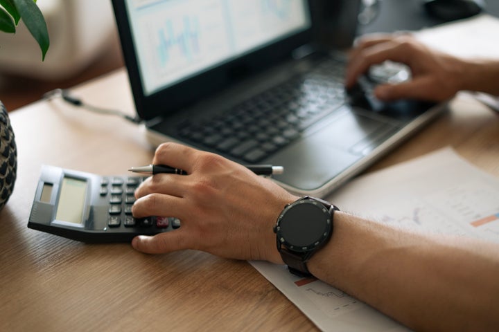 Close-up Young man hand using calculator and laptop at home