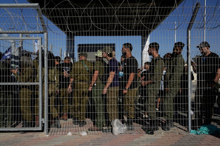 Israeli soldiers gather at the gate to the Sde Teiman military base, as people protest in support of soldiers being questioned for allegedly sexually abusing a Palestinian detainee.