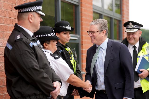 British Prime Minister Sir Keir Starmer, second right, greets members of the West Midlands Police Force as he arrives at Arden Academy in Solihull, West Midlands, England, Thursday Aug. 8, 2024. 