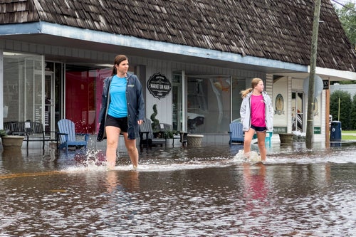 Emily Peterson Dowless, left, walks past her business Market on Main as residual rain water floods the downtown area caused by Tropical Storm Debby, on Aug. 8, 2024, in Bladenboro, NC.