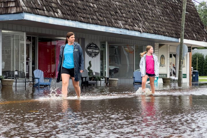 Emily Peterson Dowless, left, walks past her business Market on Main as residual rainwater floods the downtown area caused by Tropical Storm Debby, on August 8, 2024, in Bladenboro, NC.