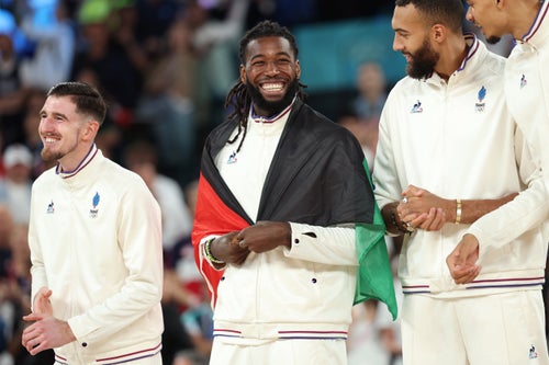 PARIS, FRANCE - AUGUST 10: Silver medalist Mathias Lessort #26 of Team France smiles while wearing the flag of Martinique on the podium during the Men's basketball medal ceremony on day fifteen of the Olympic Games Paris 2024 at Bercy Arena on August 10, 2024 in Paris, France. (Photo by Gregory Shamus/Getty Images)