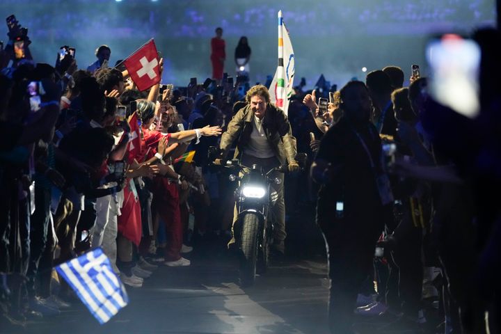 Πάνω στη μοτοσικλέτα και με την Ολυμπιακή σημαία αναχωρεί από το Παρίσι για το Λος Άντζελες. (AP Photo/Ashley Landis)