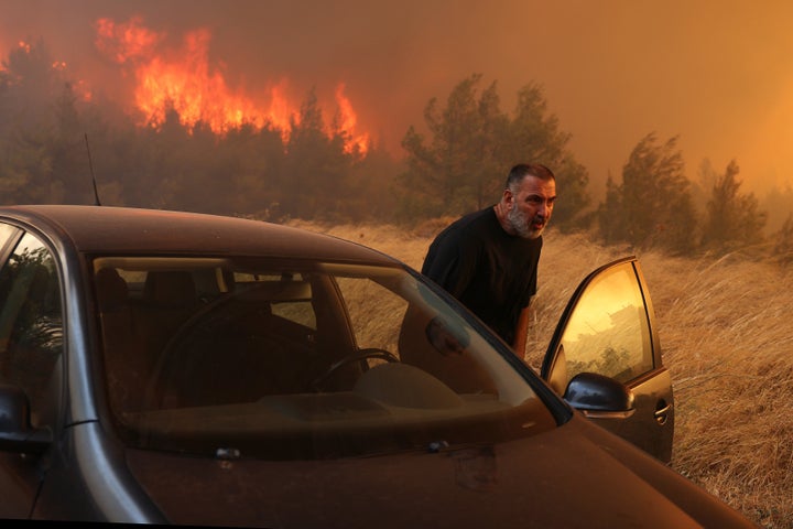 A man evacuates his house during a wildfire in Dione near Athens, Greece, on Aug. 12, 2024. A major fire that broke out Sunday in the northeastern town of Varnavas in Greece's Attica region continues to rage, forcing residents of nearly 10 villages to evacuate in the very early hours of Monday after many homes were damaged, local media reported.