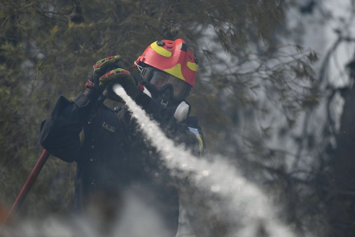 A firefighter operates in Dioni, northeast of Athens, Greece, Monday, Aug. 12, 2024. Hundreds of firefighters backed by dozens of water-dropping planes and helicopters were battling the flames from first light Monday, with a major forest fire that began the previous day raging out of control on the fringes of Athens, fanned by strong winds. (AP Photo/Michael Varaklas)