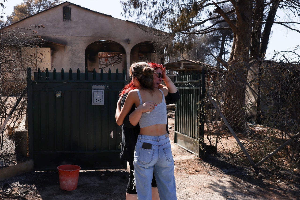 ΑΘΗΝΑ, ΕΛΛΑΔΑ - 13 ΑΥΓΟΥΣΤΟΥ: Δύο γυναίκες αντιδρούν έξω από το καμένο σπίτι τους, στις 13 Αυγούστου 2024. (Photo by Costas Baltas/Anadolu via Getty Images)