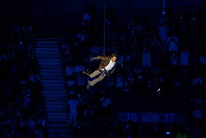 Cruise abseiled into the stadium, rode off on a motorcycle and, in a pre-taped clip, skydived.