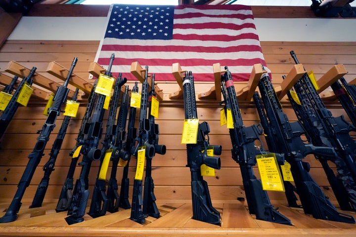 A variety of AR-15-style rifles are displayed under an American flag at the Kittery Trading Post, Friday, Aug. 9, 2024, in Kittery, Maine. 