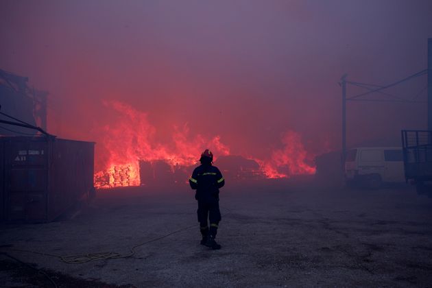 Πυροσβέστης μπροστά από φλεγόμενη επιχείρηση κατά τη διάρκεια της μεγάλης φωτιάς στη βορειοανατολική Αττική - 12 Αυγούστου 2024