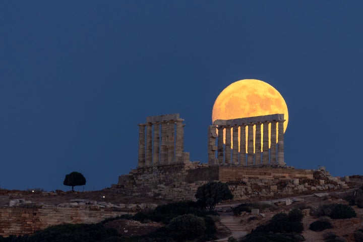 The moon rises behind the ancient marble temple of Poseidon at Cape Sounion, about 70 Km (45 miles) south of Athens, Greece, Saturday, July 20, 2024. (AP Photo/Yorgos Karahalis)