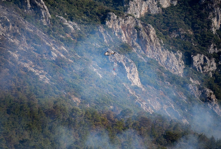 IZMIR, ΤΟΥΡΚΙΑ - 18 ΑΥΓΟΥΣΤΟΥ: Ένα ελικόπτερο που παίρνει νερό από το φράγμα Tahtali ρίχνει νερό για να σβήσει τη φωτιά που ξέσπασε στην περιοχή Menderes, καθώς οι πυροσβέστες απαντούν στις πυρκαγιές από ξηράς και αέρος στη Σμύρνη της Τουρκίας στις 18 Αυγούστου 2024. (Photo by Mahmut Serdar Alakus/Anadolu via Getty Images)