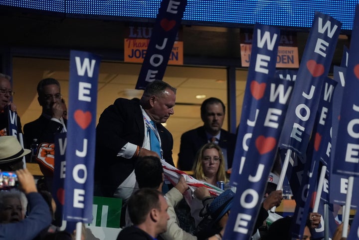 A protest banner is removed by a law enforcement officers as Biden speaks during the Democratic National Convention Monday.