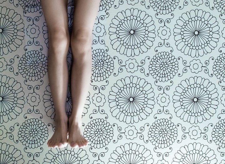 Woman legs in front of wallpaper of floral print.