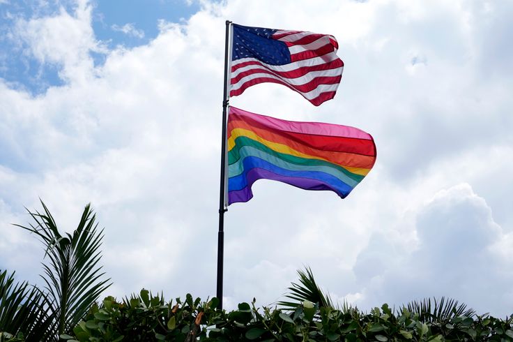 An American flag flies with a pride flag outside a home in Wilton Manors, Florida. It was reported this week that Florida’s official tourism website has quietly scrubbed a page promoting LGBTQ-friendly travel destinations.