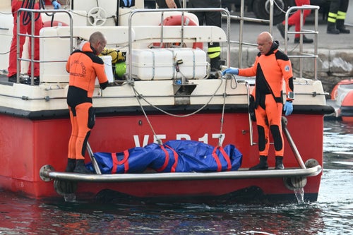 TOPSHOT - Divers of the Vigili del Fuoco, the Italian Corps. of Firefighters arrive in Porticello harbor near Palermo, with a body bag at the back of the boat on August 22, 2024, three days after the British-flagged luxury yacht Bayesian sank. Divers searching for six missing people following the sinking of a superyacht off Sicily in a storm have found fifth bodies. The Bayesian, which had 22 people aboard including 10 crew, was anchored some 700 metres from port before dawn when it was struck by a waterspout. Among the six missing were UK tech entrepreneur Mike Lynch and his 18-year-old daughter Hannah, and Jonathan Bloomer, the chair of Morgan Stanley International, and his wife Judy. (Photo by Alberto PIZZOLI / AFP) (Photo by ALBERTO PIZZOLI/AFP via Getty Images)