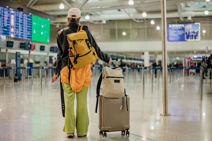 Young stylish woman with bag pack and luggage in the airport