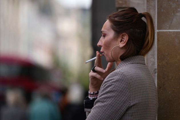 A woman smokes on a street in London.