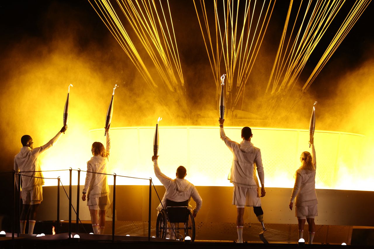 France's paralympic torchbearers, Charles-Antoine Kaoukou, Nantenin Keita, Fabien Lamirault, Alexis Hanquinquant and Elodie Lorandi, hold the Paralympic flame in front of the Paralympic cauldron.