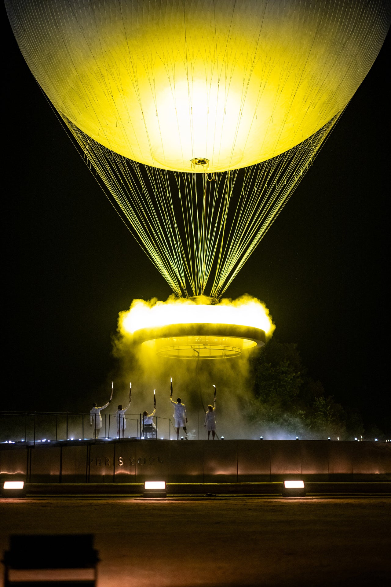 The cauldron, attached to a balloon, ascends after it's lit by torchbearers.