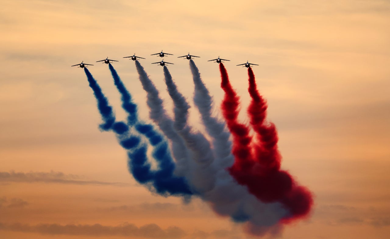 The Patrouille acrobatique de France perform a flyby whilst releasing smoke in the colours of the French flag.