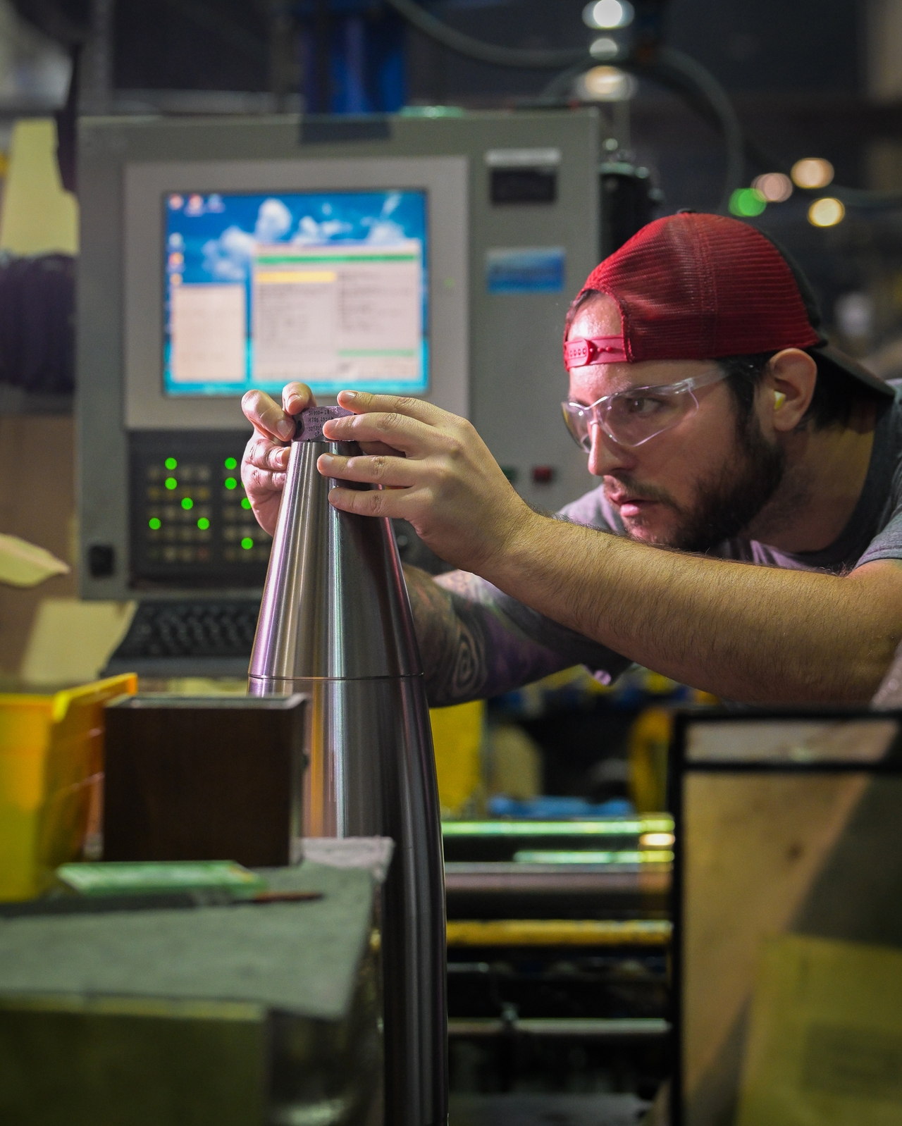 A worker places a nose on an almost complete 155 mm M795 artillery projectile.