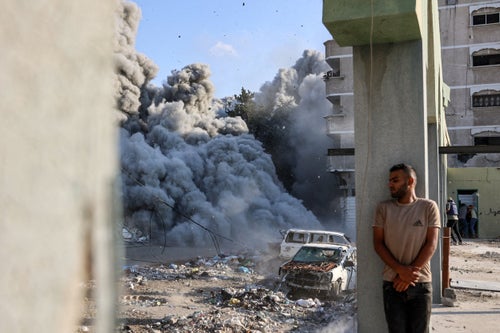A man takes cover behind a column as an explosion propagates smoke and dust during an Israeli strike which reportedly targeted a school in the Zeitoun district on the outskirts of Gaza City, on Sept. 1, 2024.