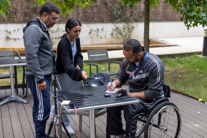 Fadi Aldeeb, the only Palestinian athlete at the Paralympic Games, signs an autograph for a young fan during an interview with The Associated Press in Paris, Tuesday, Sept. 3, 2024. (AP Photo/Ciaran Fahey)