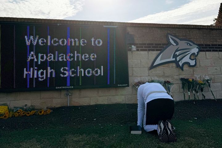 Eine Person kniet am Donnerstag, dem 5. September, vor Blumen, die vor dem Eingang der Appalachian High School in Winder, Georgia, aufgestellt sind.